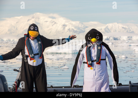 Crew members of an expedition cruise to Antarctica in a Zodiak in Fournier Bay in the Gerlache Strait on the Antarctic Peninsular, dressed up as penguins. The Antarctic Peninsular is one of the most rapidly warming areas on the planet. Stock Photo