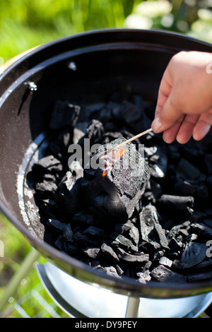 Striking a matchstick, burn up a charcoal in barbecue grill, prepare for cooking Stock Photo
