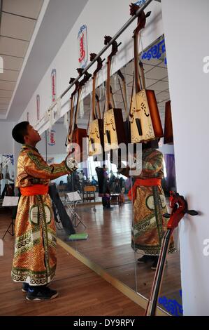 Bayan Nur, China's Inner Mongolian Autonomous Region. 10th Apr, 2014. A student gets off a Matouqin, a horse-head musical instrument, before class at a middle school for the Mongolian ethnic group, in Bayan Nur, north China's Inner Mongolian Autonomous Region, April 10, 2014. Folk art courses such as archery, folk costumes, folk dance, wrestling were set up as selective courses for students here. © Zhi Maosheng/Xinhua/Alamy Live News Stock Photo