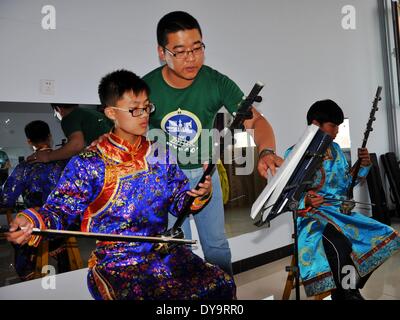 Bayan Nur, China's Inner Mongolian Autonomous Region. 10th Apr, 2014. Students learn to play sihu, a musical instrument, at a middle school for the Mongolian ethnic group, in Bayan Nur, north China's Inner Mongolian Autonomous Region, April 10, 2014. Folk art courses such as archery, folk costumes, folk dance, wrestling were set up as selective courses for students here. © Zhi Maosheng/Xinhua/Alamy Live News Stock Photo