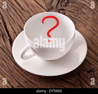 Empty white cup with red question mark in it on old wooden table. Stock Photo