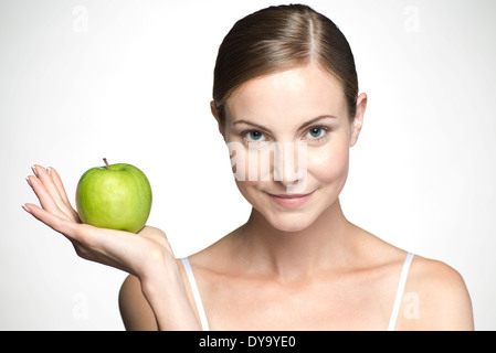 Young woman holding up green apple Stock Photo