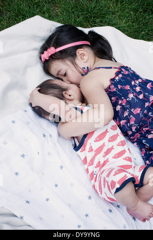 Little girl with baby brother lying on blanket outdoors Stock Photo