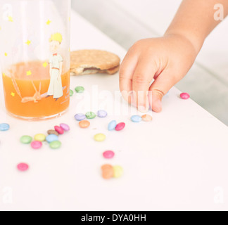 Child picking up candies from table Stock Photo