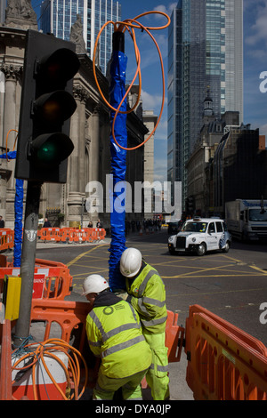 Two construction workmen manhandle a new post on Bishopsgate (Street) in the City of London, the capital's financial district. Stock Photo