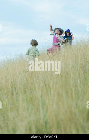 Children playing in tall grass on hillside Stock Photo