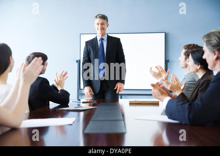 Business associates applauding colleague at meeting Stock Photo