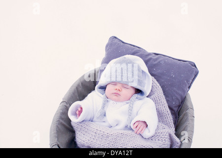 Baby sleeping in bassinet in snow Stock Photo