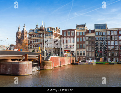 AMSTERDAM, NETHERLANDS - MARCH 19, 2014: Colorful building facades and bridge with walking people. Damrak street Stock Photo