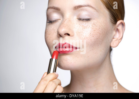 Young woman putting on lipstick Stock Photo