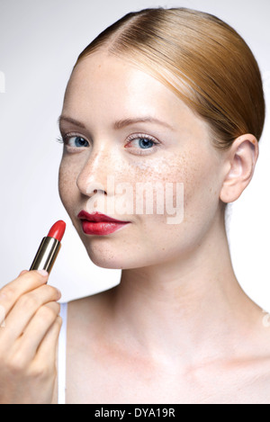 Young woman putting on lipstick Stock Photo