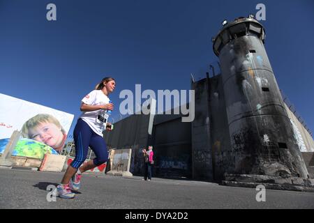 Bethlehem, West Bank. 11th Apr, 2014. Participants run next to the controversial Israeli barrier during the second Palestine International Marathon in the West Bank city of Bethlehem on April 11, 2014. About 3,000 runners participated in the marathon this year, Palestinian officials said. Credit:  Luay Sababa/Xinhua/Alamy Live News Stock Photo