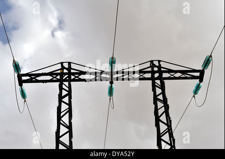 High voltage three phase electrical power lines with glass insulators at top of pylon Stock Photo