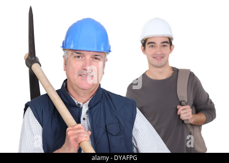 mature manual worker and young apprentice in background Stock Photo