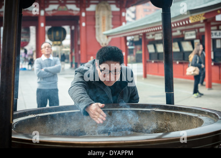 Man burning incense in the main courtyard at Senso-ji Temple in the Asakusa district of Tokyo. Stock Photo
