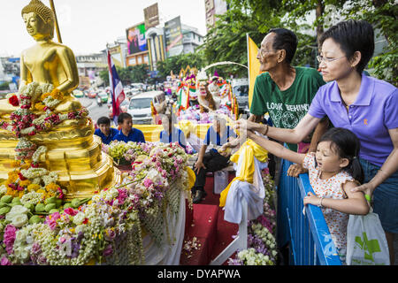 Bangkok, Thailand. 12th Apr, 2014. People bathe the Phra Buddha Sihing statue with scented oils. The Phra Buddha Sihing, a revered statue of the Buddha, is carried by truck through the streets of Bangkok so people can make offerings and bathe it in scented oils. Songkran is celebrated in Thailand as the traditional New Year's from 13 to 16 April.  The traditional Thai New Year has been a national holiday since 1940, when Thailand moved the first day of the year to January 1. Credit:  ZUMA Press, Inc./Alamy Live News Stock Photo