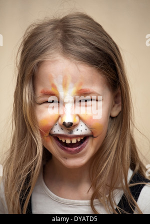 closeup portrait of little girl with cat painting makeup on the face looking at camera Stock Photo