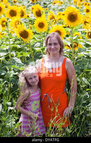 smiling caucasian woman and little girl standing on sunflowers field background Stock Photo