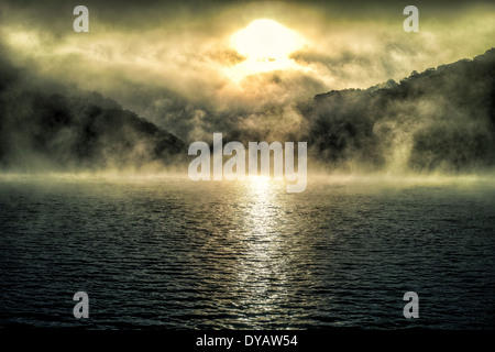 Sunrise Over Hills and Water with Fog Stock Photo
