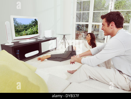 Portrait of young happiness couple watching tv lying on bed Stock Photo