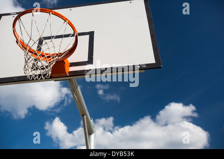 Basketball hoop against lovely blue summer sky with some fluffy white clouds Stock Photo
