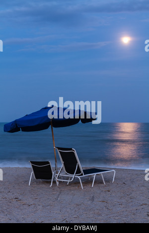 Full Moon Rising over as set of beach chairs and umbrella on the Beach on Amelia Island in Florida. Stock Photo