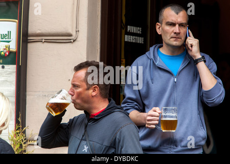 Two men drinking beer outside a bar on a street, Prague Old Town Czech Republic daily life Stock Photo