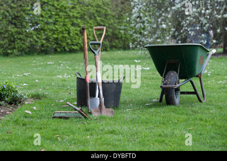 Wheelbarrow with garden tools and trugs at RHS Wisley Gardens, Surrey, England Stock Photo