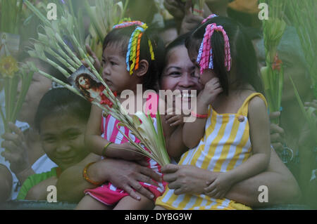 Manila, Philippines. 13th Apr, 2014. MANILA, Philippines - A woman and her children get doused by the priest with holy water before the celebration of the Holy Mass on Palm Sunday at the National Shrine of Our Mother of Perpetual Help in Baclaran, Paranaque city, south of Manila on 13 April 2014. Palm Sunday is celebrated by Filipino Catholics commemorating the arrival of Jesus into Jerusalem and marks the start of the Holy Week, being observed by Catholics worldwide. Credit:  George Calvelo/NurPhoto/ZUMAPRESS.com/Alamy Live News Stock Photo