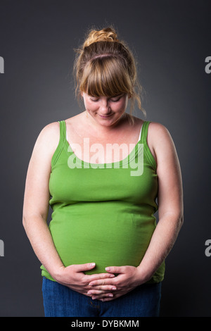 Happy young prengant woman in studio - dark background Stock Photo