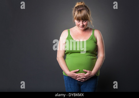 Happy young prengant woman in studio - dark background Stock Photo