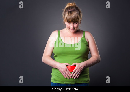Happy young prengant woman in studio - dark background Stock Photo