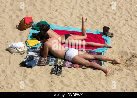 young couple on towels face down shoes bags attractive holiday resting Stock Photo