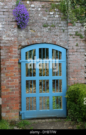 Blue garden gate in walled garden Uk Stock Photo