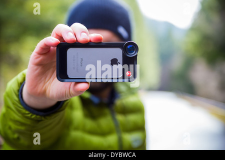 Oakridge, Oregon, USA - February 19,2014: Photographer using an iPhone 5S with Manfrotto lens attached outdoors. Stock Photo