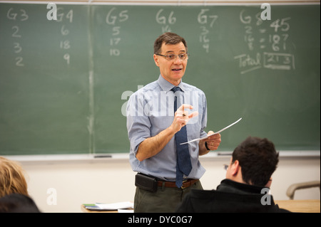 Teacher explaining to students in front of a chalkboard Stock Photo