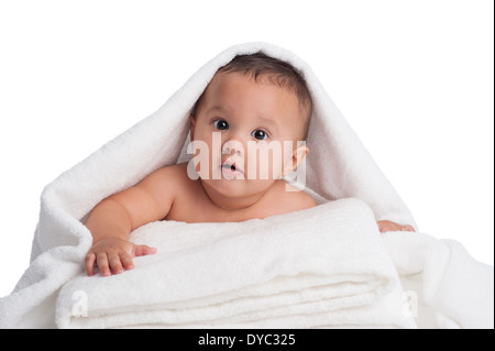 A seven month old, Hispanic baby boy peeking out from under a white towel. Stock Photo