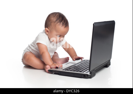 A seven month old, Hispanic baby boy typing on a laptop computer. Stock Photo