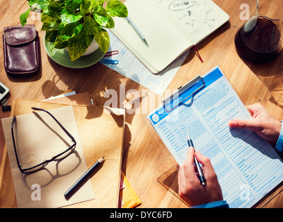 Businessman Filling Out a Form on Wooden Table Stock Photo