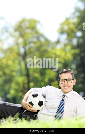 Young man with soccer ball lying on grass outdoors Stock Photo