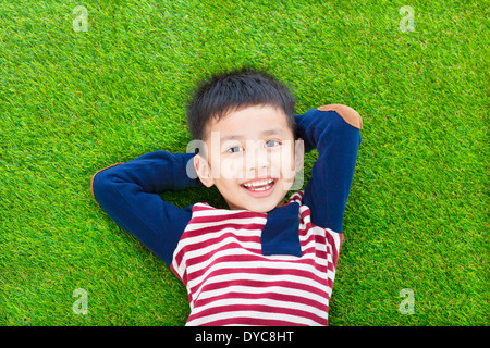 happy kid lying and holding his head on a meadow Stock Photo