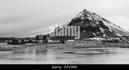 Black and white image of the house in the foothills of the mountain in Iceland. Stock Photo