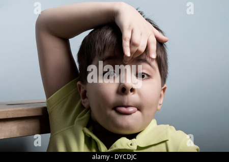 portrait of a cute boy of seven, pretending to be a clown and showing his tongue, concept of misbehavior Stock Photo