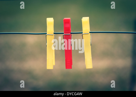 Three clothes pegs hanging on a clothesline Stock Photo