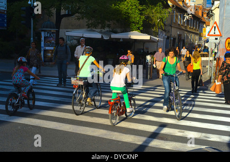 Unidentified people crossing street and riding bicycles on the street of Ljubljana. The downtown quarter usually attracts lots Stock Photo