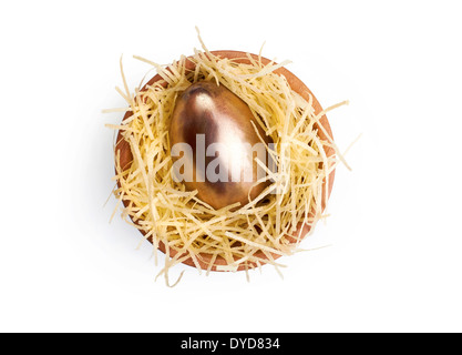 One large Golden Easter Egg in a wooden bowl with edible straw on a white background. Stock Photo