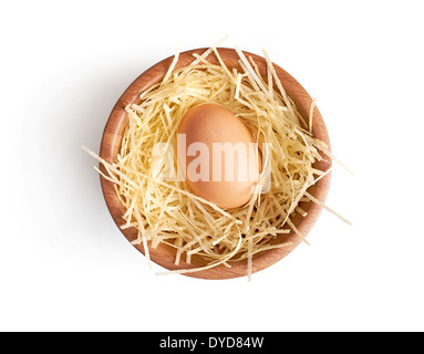 A fresh hens egg on some straw in a wooden bowl on a white background. Stock Photo