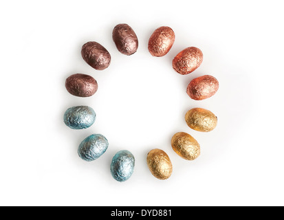 A circle of chocolate Easter Eggs wrapped in coloured tin foil on a white background. Stock Photo