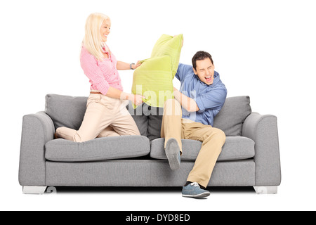 Man and woman having a pillow fight on couch Stock Photo