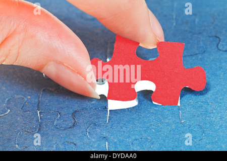 attaching the last red piece of puzzle in free space in assembled jigsaw puzzles Stock Photo